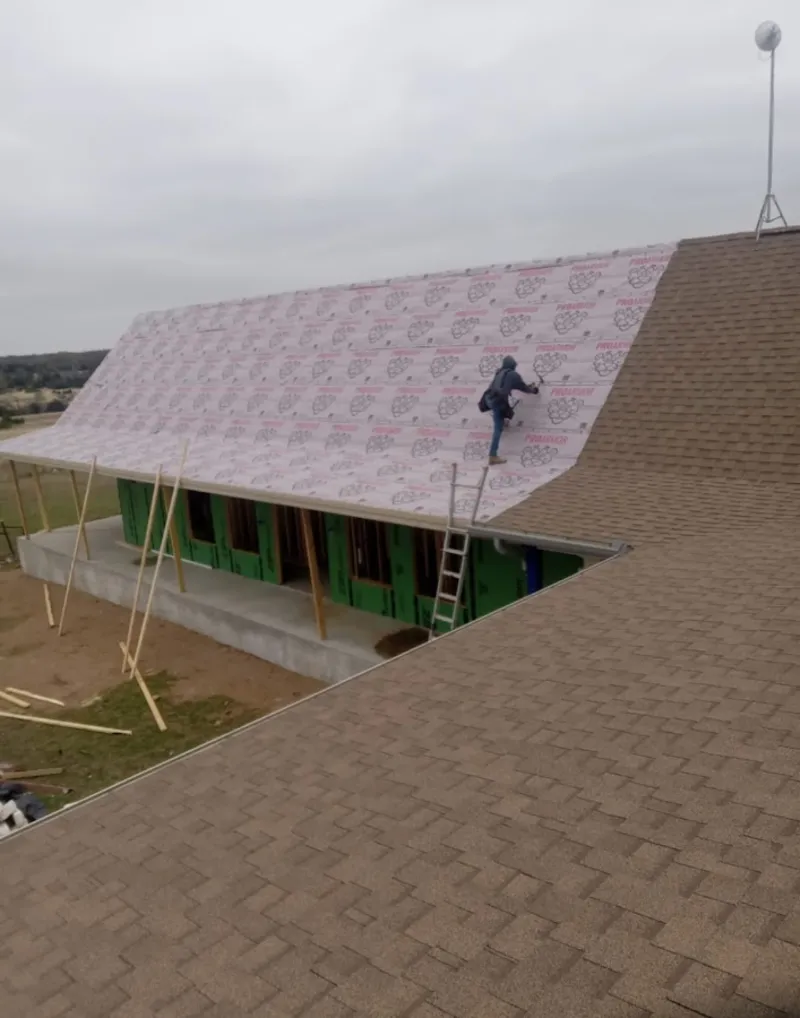 Worker preparing underlayment for a metal roof installation in West Bridgewater